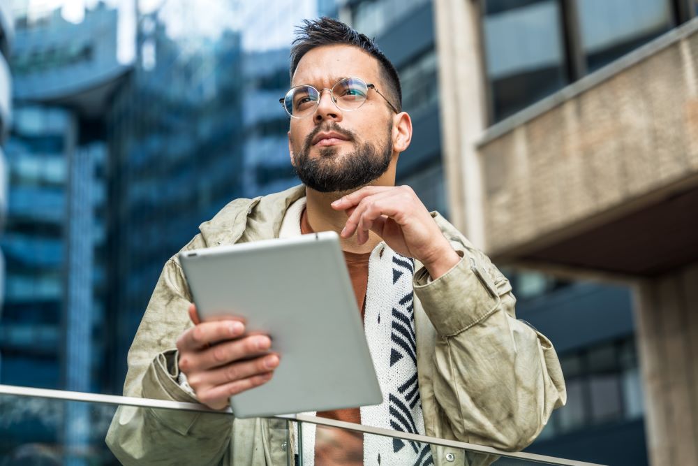 Young businessman standing near the office building looking away